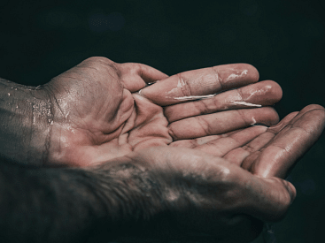 Wet hands cupped together against a dark background.