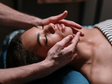 A woman enjoying a calming face massage in a spa.