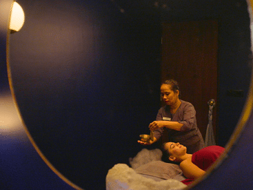A woman receiving a relaxing treatment in a dimly lit spa room.