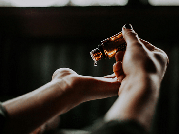 A person using droplets of oil on their hand, typically for relaxation