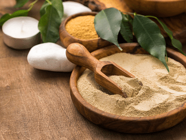Tibetan body scrub on a tray with a white stone near a plant.