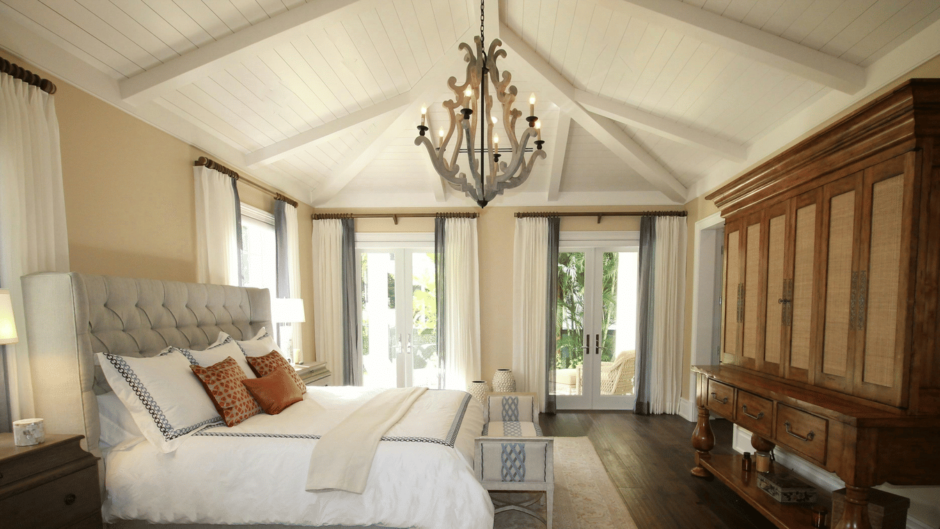 Side view image of the bed with a chandelier hanging over the double bed.