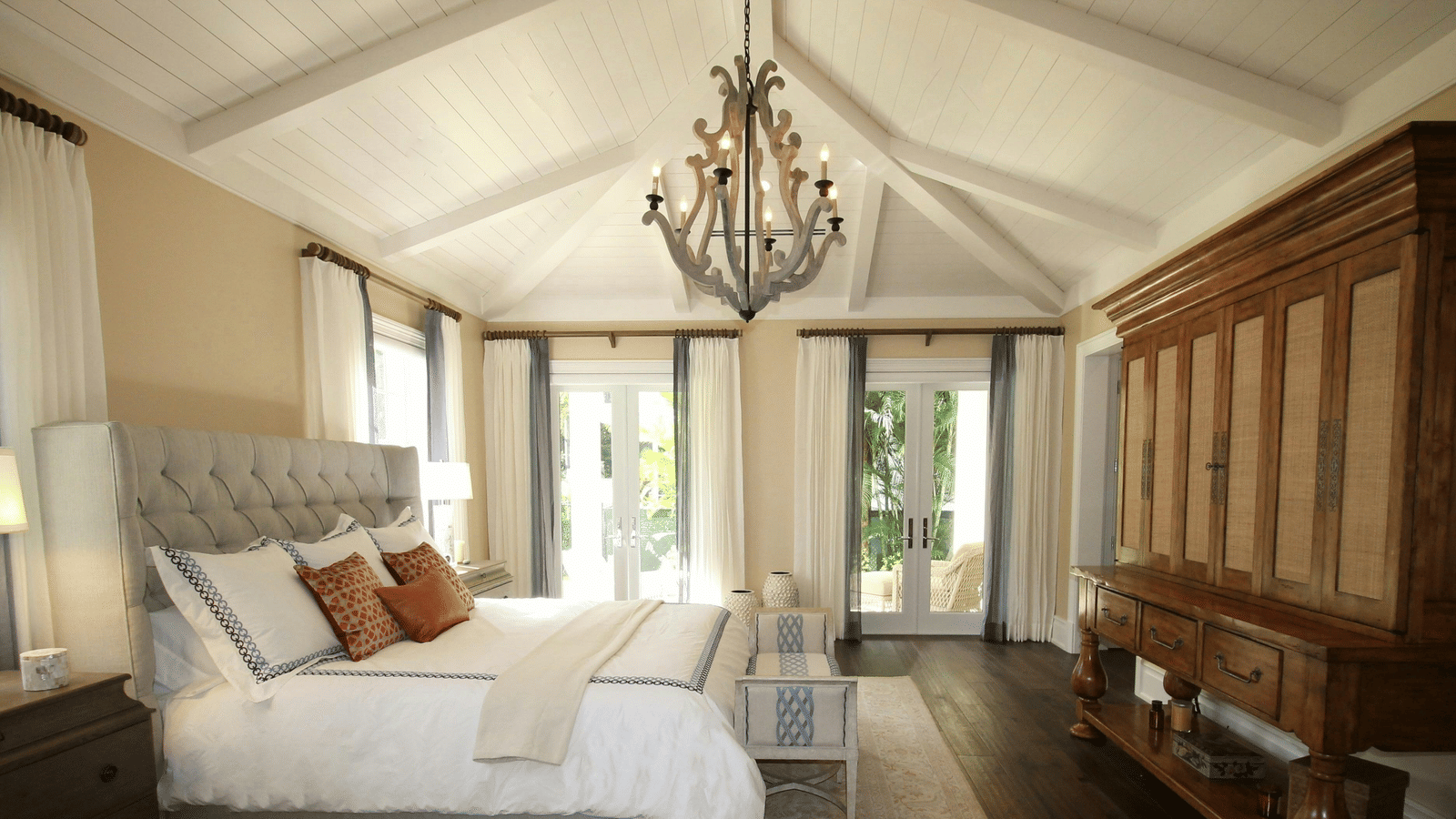 Side view image of the bed with a chandelier hanging over the double bed.