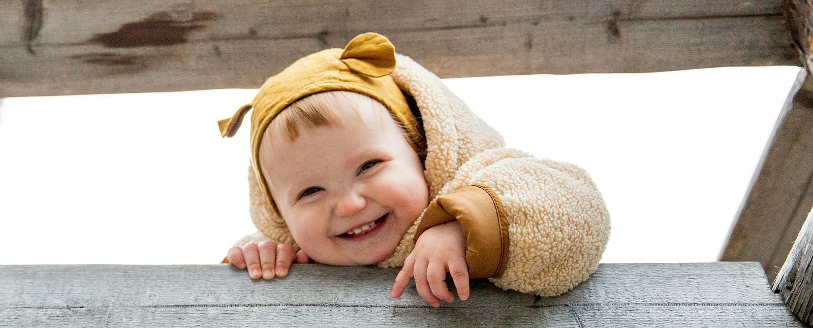 A baby wearing winter clothes smiling towards the camera