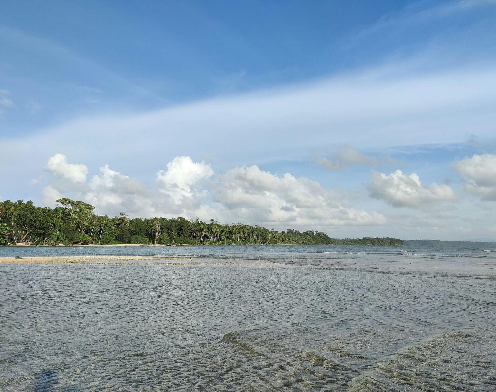 A peaceful stretch of shallow water gently meeting the sandy beach under a clear sky.