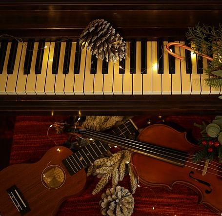 An overhead shot of piano and violin arrangement decorated with pine cones and leaves.