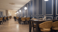 A sophisticated restaurant dining area at Pride Resort, Rajkot featuring dark panelled walls, round tables, and comfortable chairs