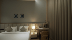  Wide angle shot of Premium Room featuring a comfortable double bed with pillows and cushions arranged over it and night lamp next to it - Pride Resort, Rajkot