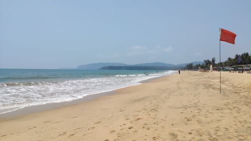 Agonda Beach with waves lapping on the beach and a hill in the background