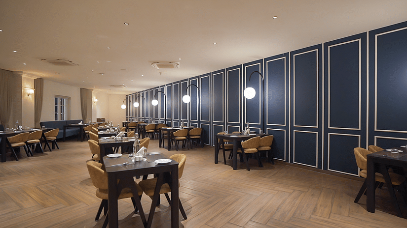 Full view shot of the restaurant at Pride Resort, Rajkot with navy blue coloured walls giving an elegant look