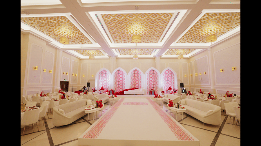 A wide view of a decorated banquet hall at La Maison, Doha, featuring a patterned ceiling and arched doorways.