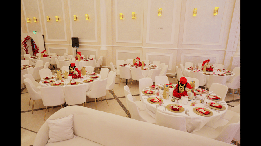 A close-up shot of a decorated table at La Maison, Doha, with a focus on floral arrangements and place settings in a banquet hall.