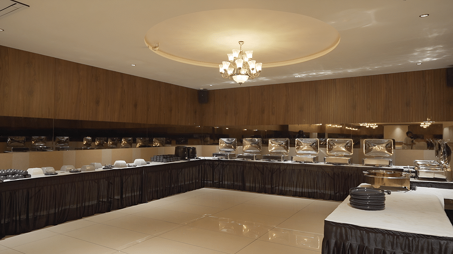 Buffet stations are prepared along the walls of imperial Hall with chandelier hanging above at Pride Resort, Rajkot. 
