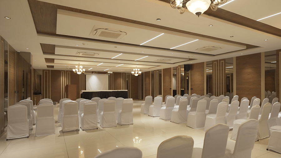 A a spacious conference at Pride Resort, Rajkot, devoid of people, filled with perfectly aligned rows of white chairs, suggesting readiness.
