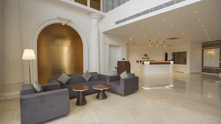 Side view shot of lavish lobby at  Pride Resort Rajkot with a reception desk, elegant decor and sofas.
