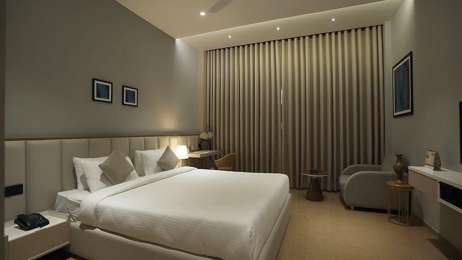 Side view shot of Superior Room featuring a comfortable double bed with pillows and cushions arranged over it - Pride Resort, Rajkot