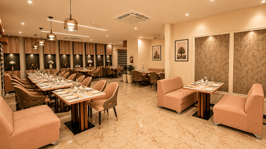 Dining area at Tulip Inn, Hoodi Whitefield, Bengaluru, with tables, armchairs, sofa seating, hanging light fixtures, and wall art.