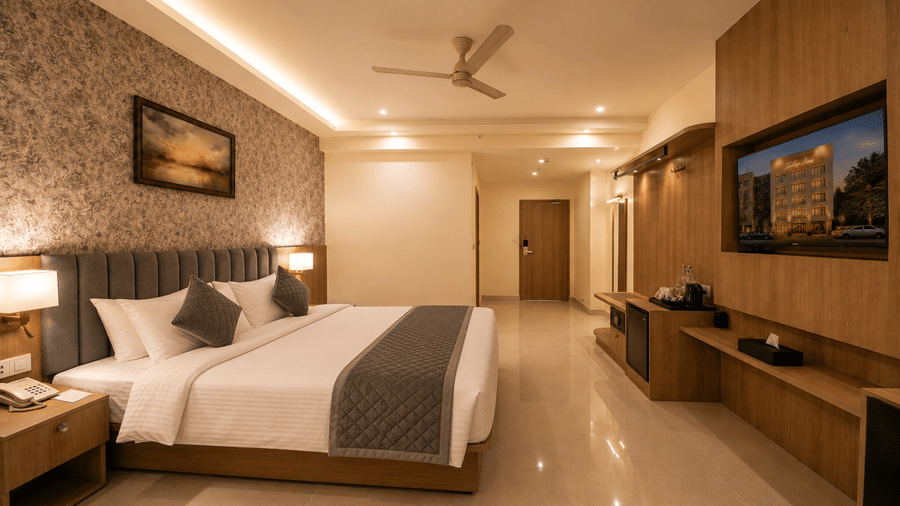 Deluxe Room at Tulip Inn, Hoodi Whitefield, Bengaluru, displaying a double bed, wall art, a television, and a refreshment counter.