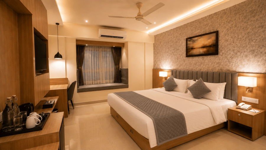 Deluxe Room at Tulip Inn, Hoodi Whitefield, Bengaluru, with a double bed, bedside tables, lamps, wall art, and a coffee setup.