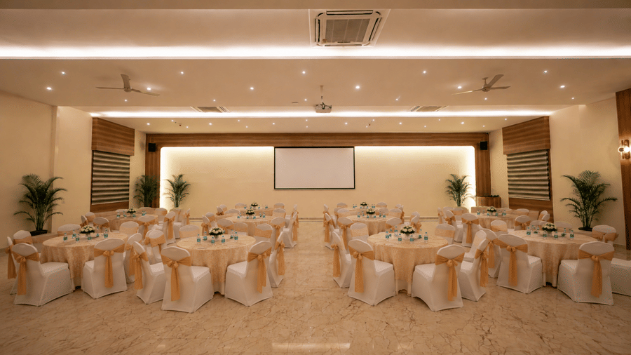 Lavender event room at Tulip Inn, Hoodi Whitefield, Bengaluru, arranged with round tables, chairs, and a projection screen at the front.