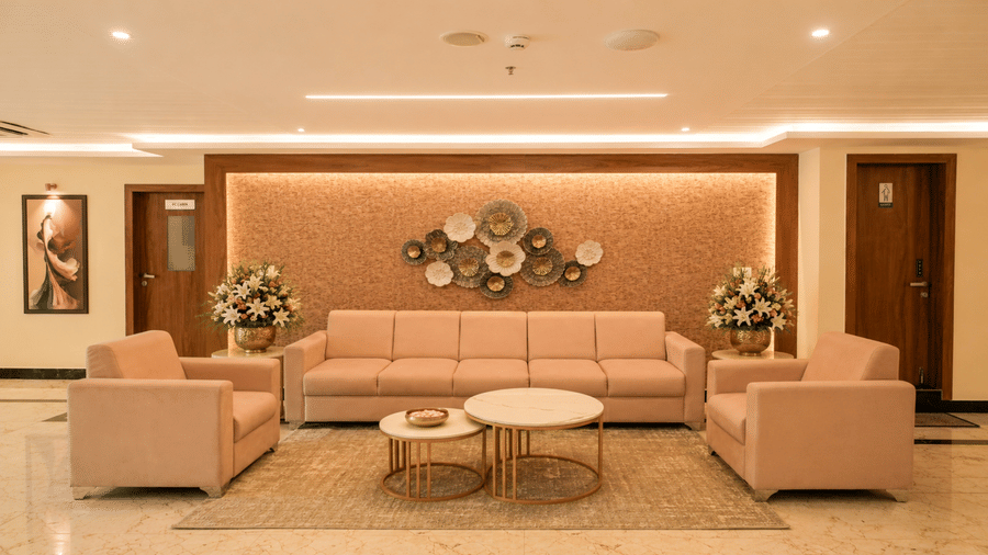 Lounge area at Tulip Inn, Hoodi Whitefield, Bengaluru, featuring sofas, armchairs, coffee tables, wall decor, and flower arrangements.