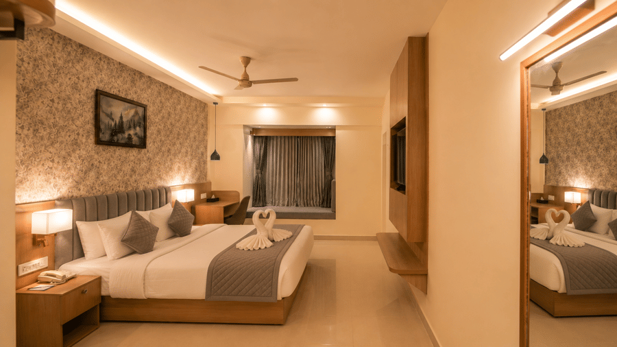 Premium Room at Tulip Inn, Hoodi Whitefield, Bengaluru, displaying a double bed, bedside lamps, wall art, mirror, and a television unit.