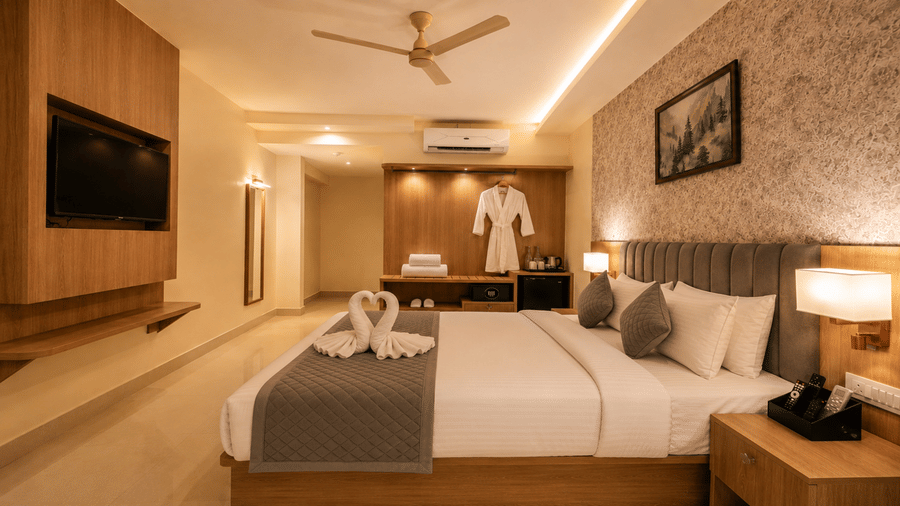 Premium Room at Tulip Inn, Hoodi Whitefield, Bengaluru, with a double bed, towel swans, wall-mounted television, and a hanging bathrobe.