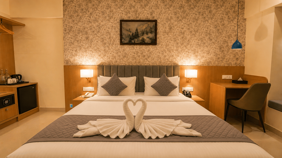 Premium Room at Tulip Inn, Hoodi Whitefield, Bengaluru, featuring a bed with folded towel swans, bedside lamps, wall art, and a desk.