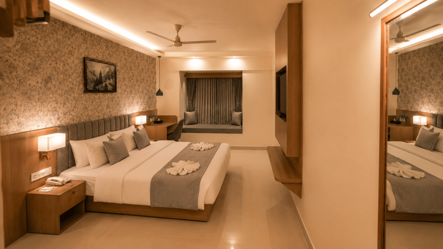 Premium Room at Tulip Inn, Hoodi Whitefield, Bengaluru, showing a double bed, bedside table, ceiling fan, mirror, and window seating.
