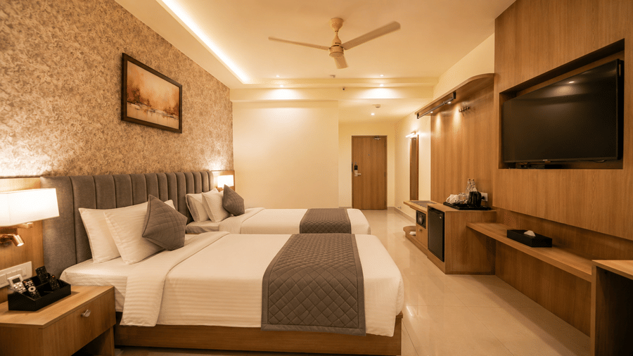 Guest Room at Tulip Inn, Hoodi Whitefield, Bengaluru, featuring two single beds, bedside lamps, wall art, and a wall-mounted television.