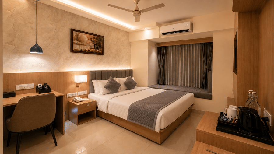 Standard Room at Tulip Inn, Hoodi Whitefield, Bengaluru, with a double bed, bedside table, desk, chair, hanging light fixture, and window seating.