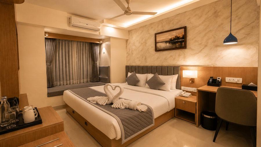 Superior King Room at Tulip Inn, Hoodi Whitefield, Bengaluru, with a double bed, towel swans, a desk, a chair, lamps, and a window seat.