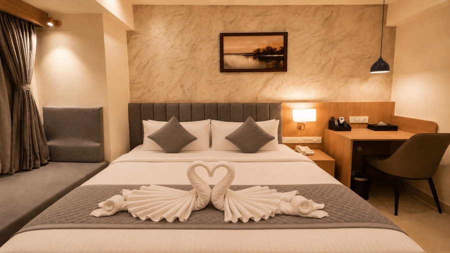 Superior King Room at Tulip Inn, Hoodi Whitefield, Bengaluru, featuring a bed with folded towel swans, pillows, wall art, and a work desk.