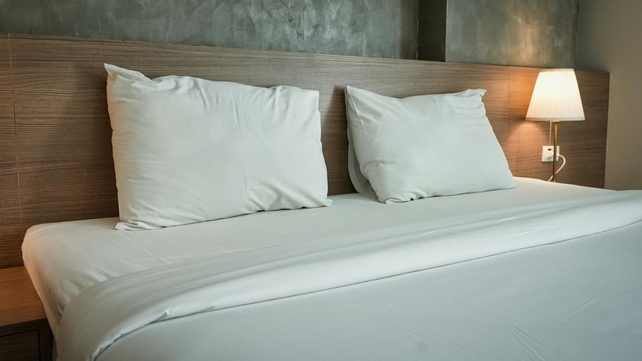 An image of a room with a bed, pillows, and lamp