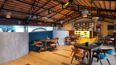 An indoor bar space at DNC Shevaroys Resort & Spa showing a mix of booth seating and standard dining tables.