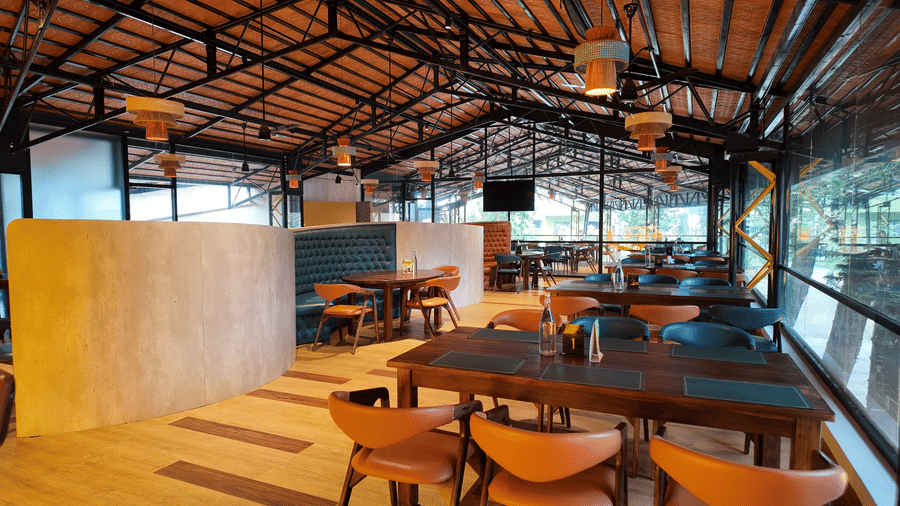 Naturally lit Above Clouds bar at DNC Shevaroys Resort & Spa with modern outdoor seating, potted plants, and an open doorway leading into a booth.