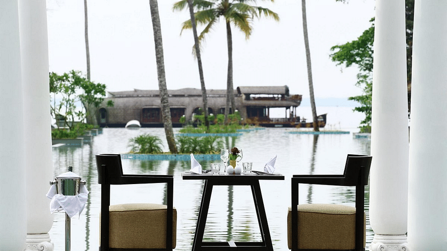 an image of Dining table setup near with swimming pool in background - Rhythm Kumarakom
