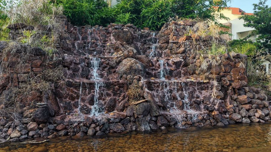 A man-made rock waterfall feature cascading water down into a shallow pool | Lords Sahyadri Resort, Shivamogga