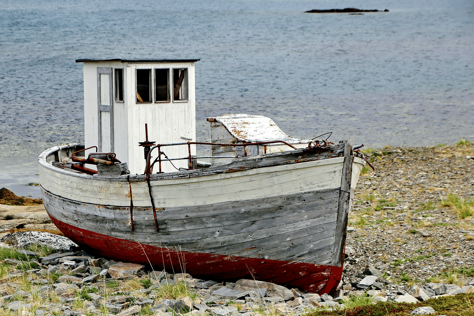a wooden boat on the shore with a water body in the background