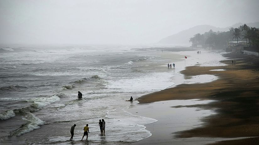 An overview of Anjuna beach in the winter months with people standing on the overlapping waves