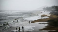 An overview of a beach with people standing on the overlapping waves
