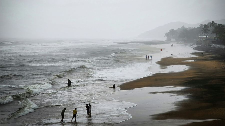 An overview of Anjuna beach in the winter months with people standing on the overlapping waves