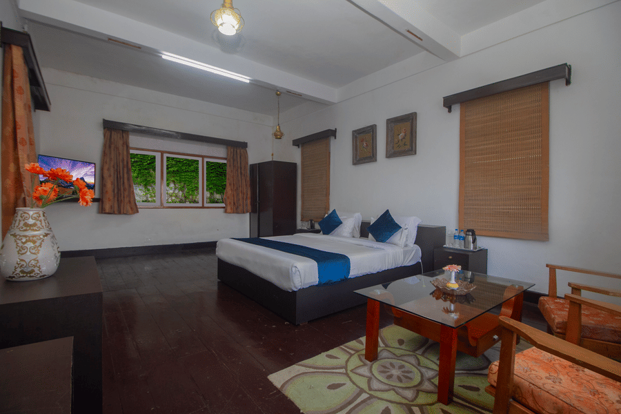 The Club King Room of Central Gleneagles Heritage Resort showcasing a double bed, wooden flooring,  seating area, and windows.