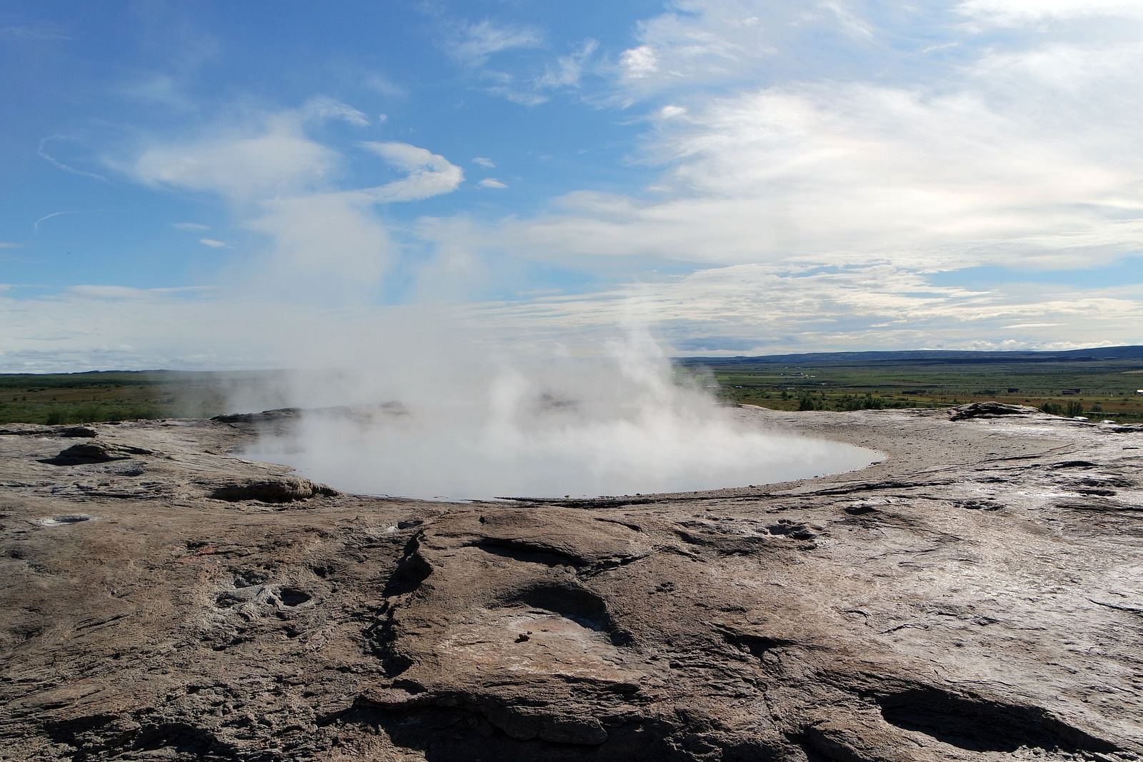 An overview of a hot spring with white clouds on blue sky in the background.