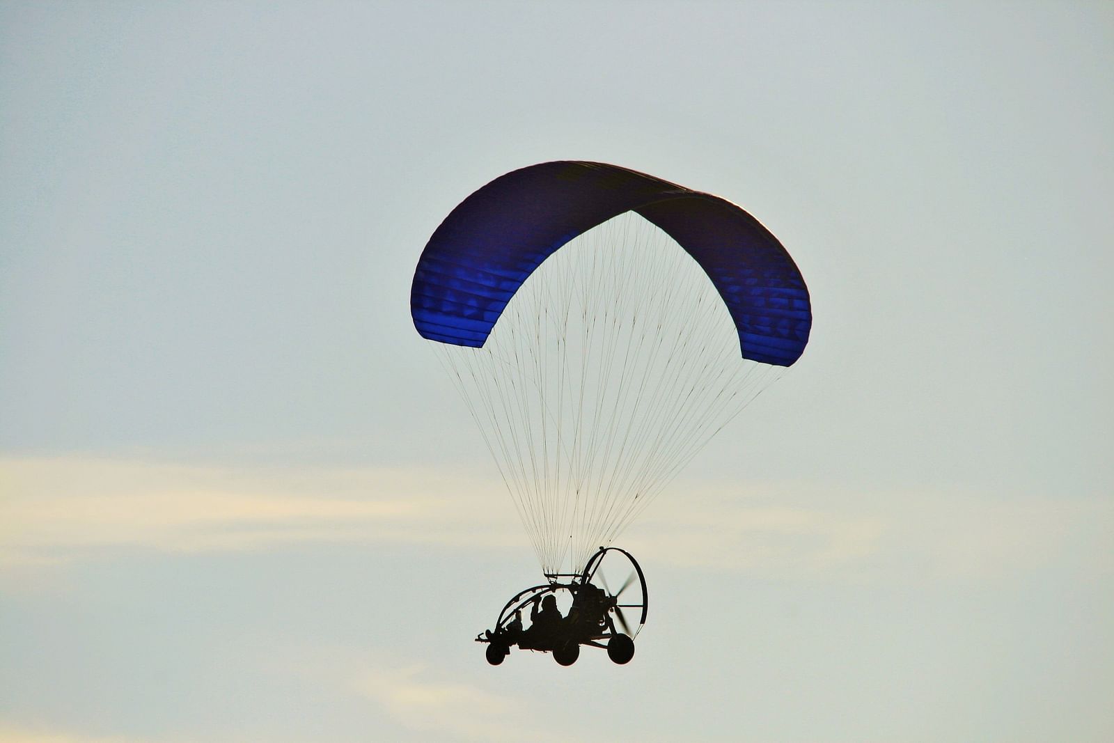 A far out view of a person using a motorised paramotor with a parachute attached.