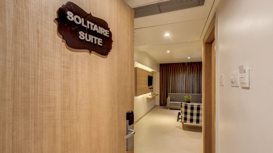 An open wooden door with a sign reading Solitaire Suite leads into a living space. This image shows the entrance to a Suite Room at The SSK Solitaire Hotel & Banquets, Mumbai Naka - Nashik.
