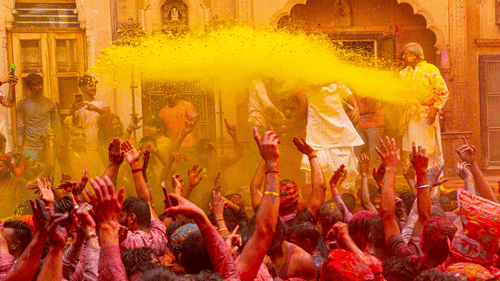People celebrating the festival of Holi with yellow powder colour thrown in the air over them.