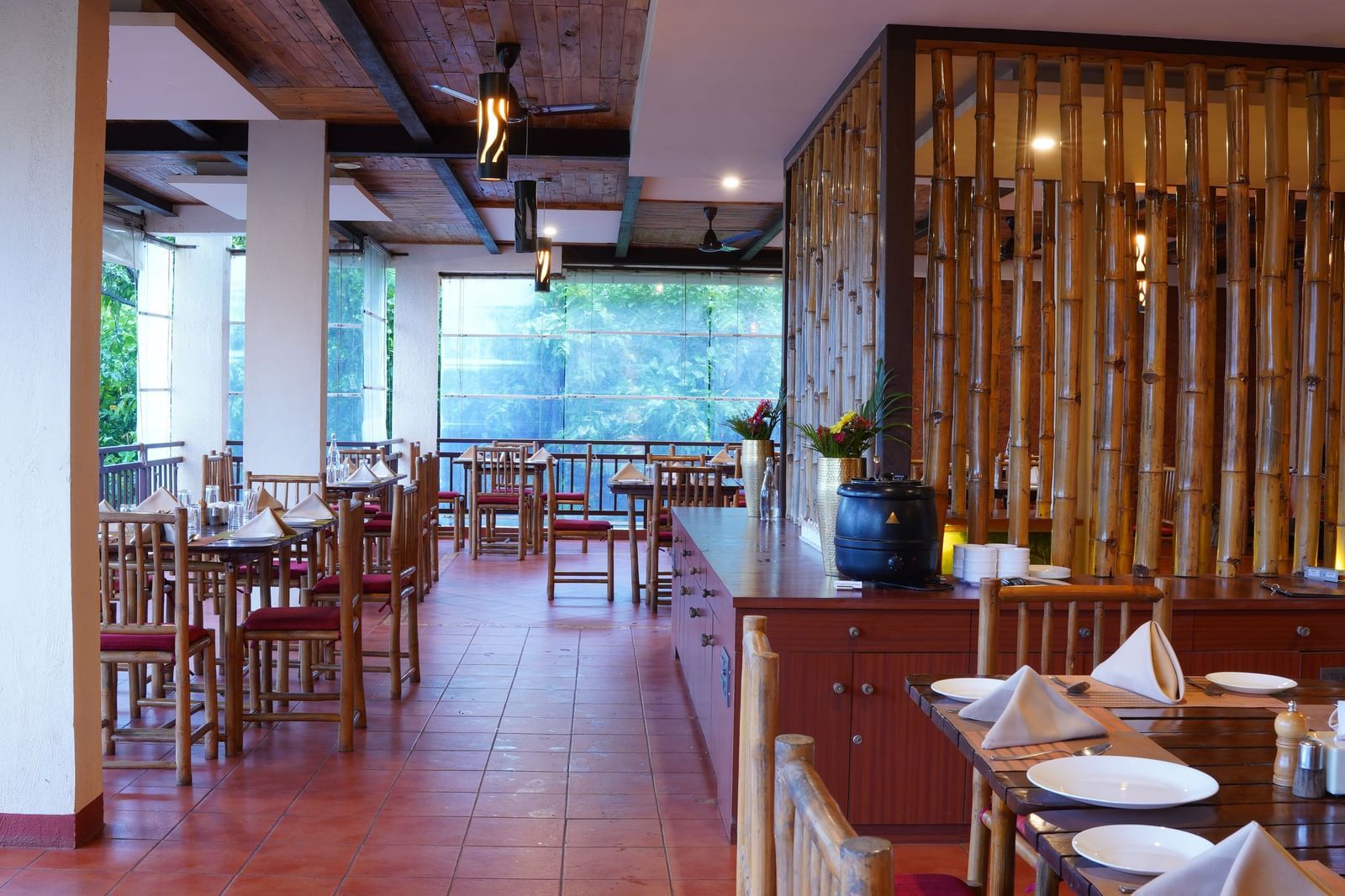 The dining area at the Top Koyna Restaurant inside Forest Escapes features tables and chairs, with natural light streaming in.