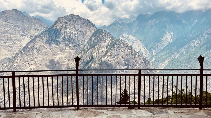 Spectacular mountain vista viewed from behind a metal railing, emphasizing the vast landscape  | Faraway Cottages, Auli