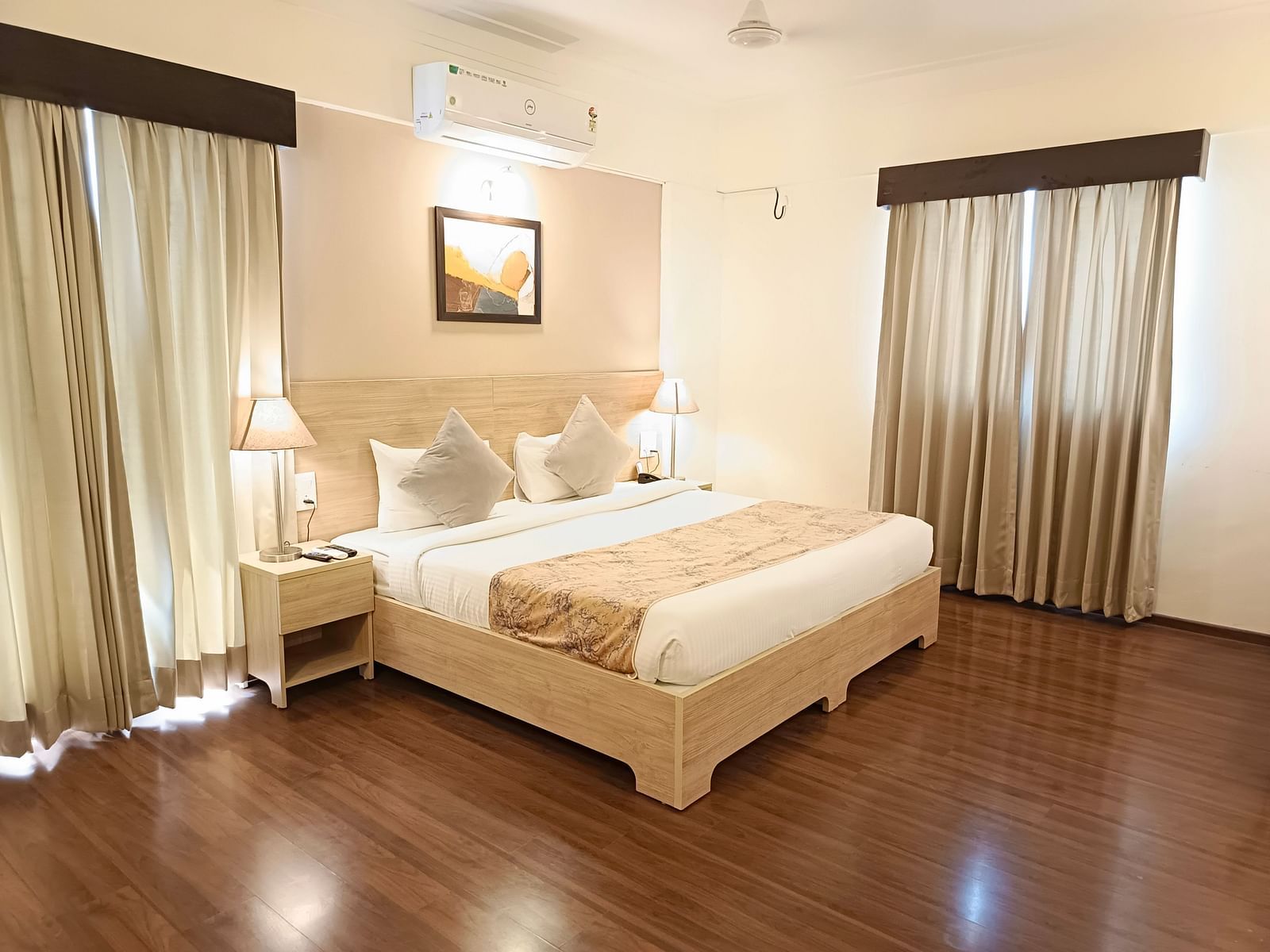 Plush bed on a well-furnished floor under warm lighting with two lamps on the nightstands on both sides of the bed inside premium studio at Starlit Suites, Shirdi